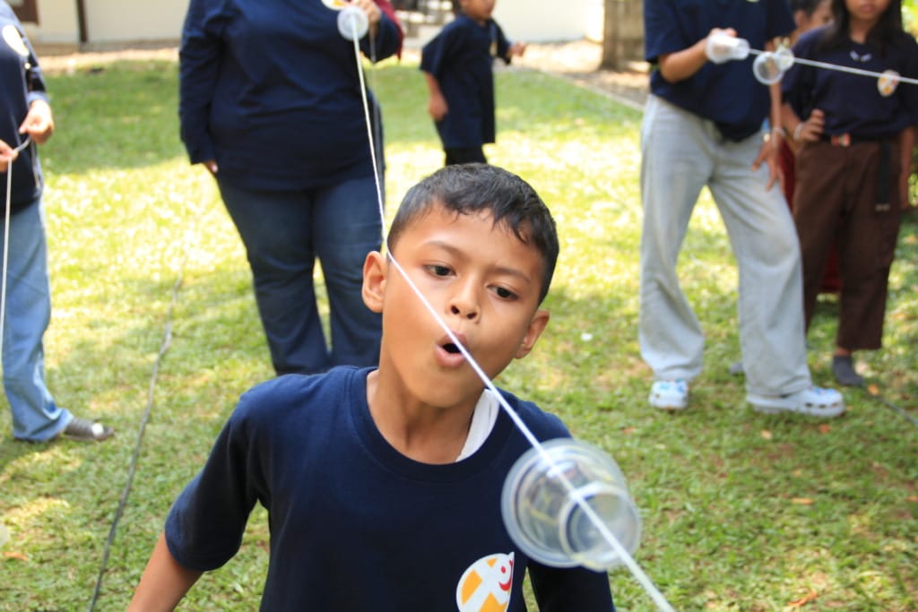 Participants seriously compete in a rope blowing contest at the Indonesian Independence Day celebration at the XSProject Foundation.