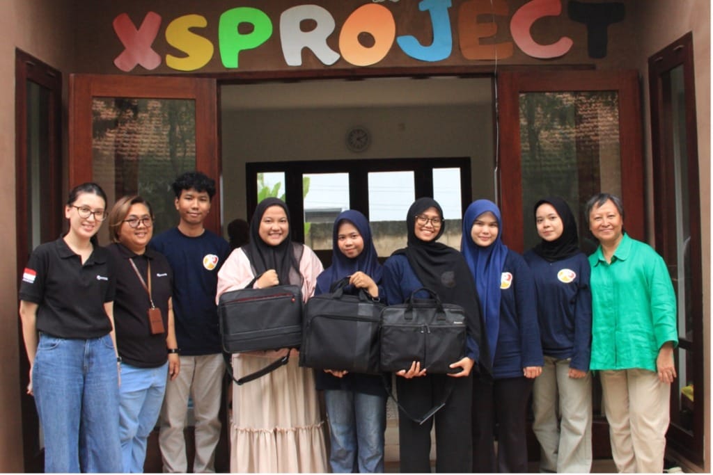 Retno (right), as chair of the XSProject Foundation’s advisory board, poses for a photo with students during the laptop handover by NTTData