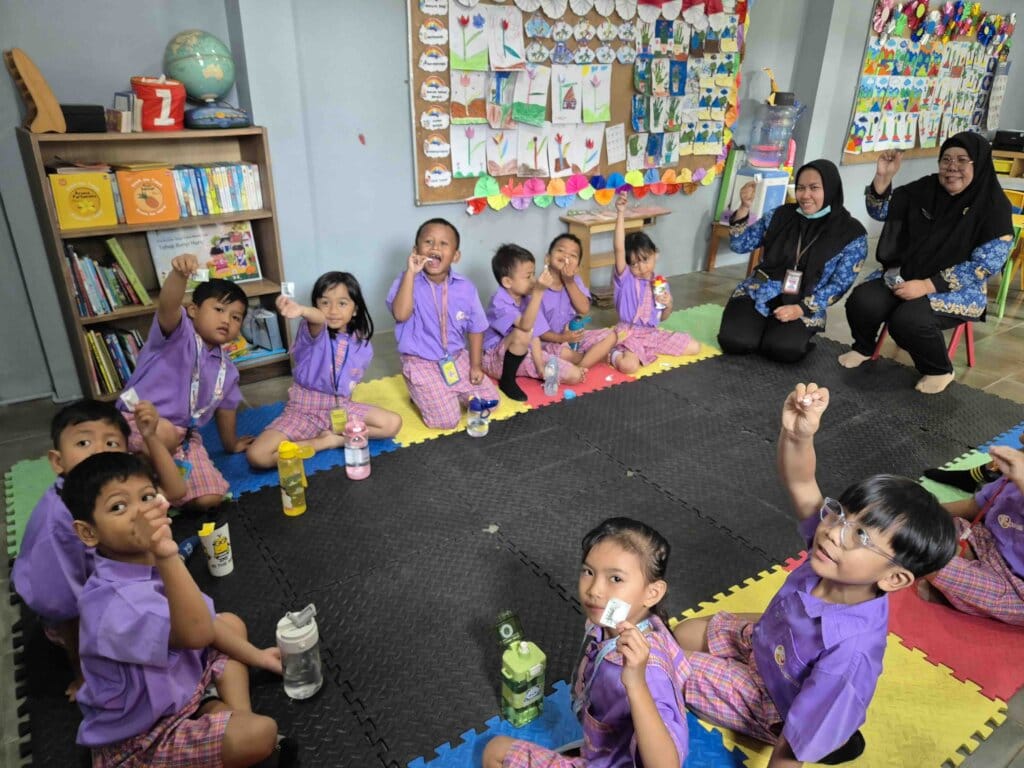 Children in classroom raising hands with cards