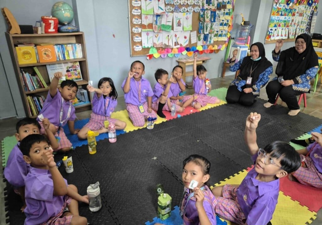 Children in classroom raising hands with cards